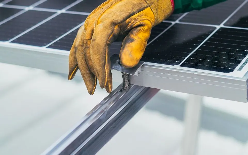 A gloved hand resting on the edge of a solar panel.