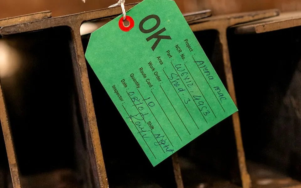 Steel sections stacked beneath an inspection tag.