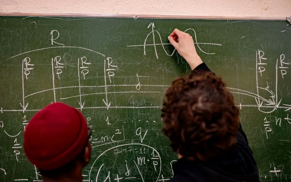 Two learners working at a blackboard, seen from behind.