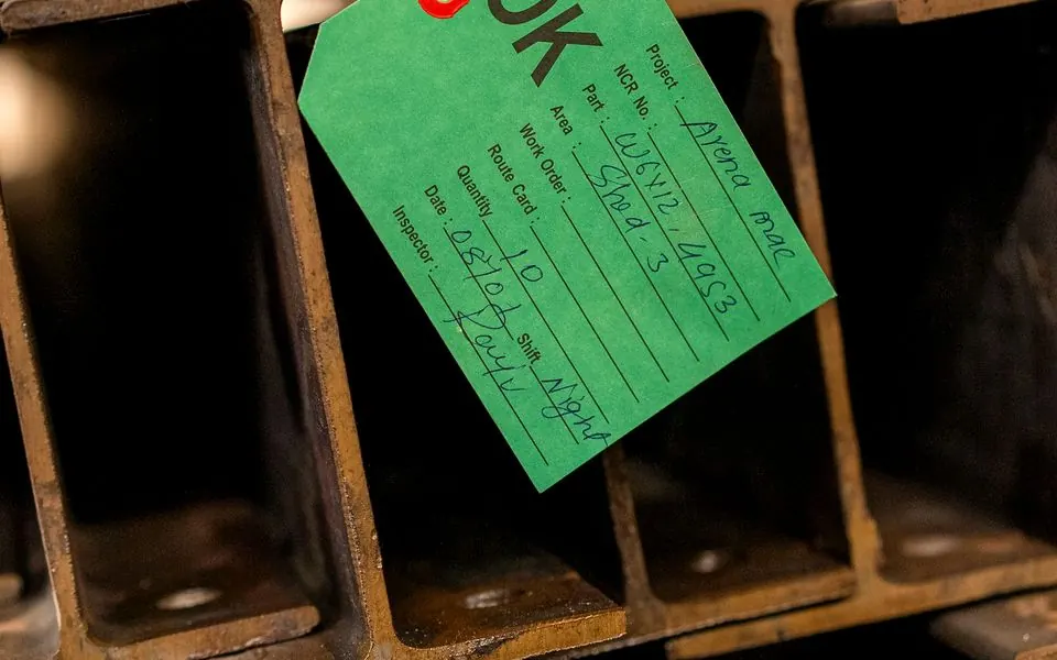 Stacked steel sections below an inspection tag.