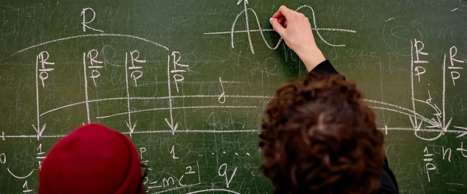 Two learners working through a problem at a blackboard.